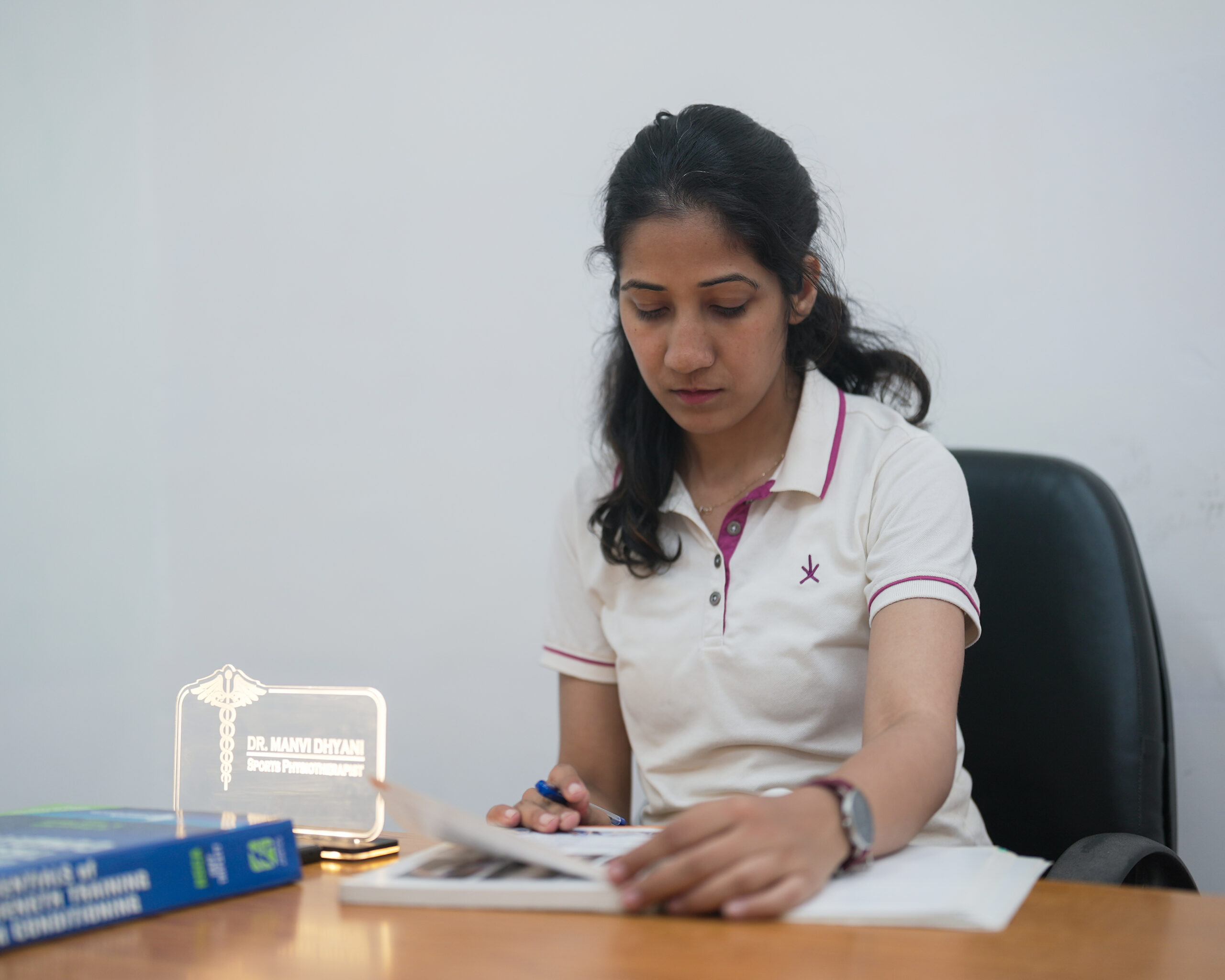 Dr. Manvi Dhyani, PT, Sports Physiotherapist reviewing patient notes at her clinic in Saket, New Delhi